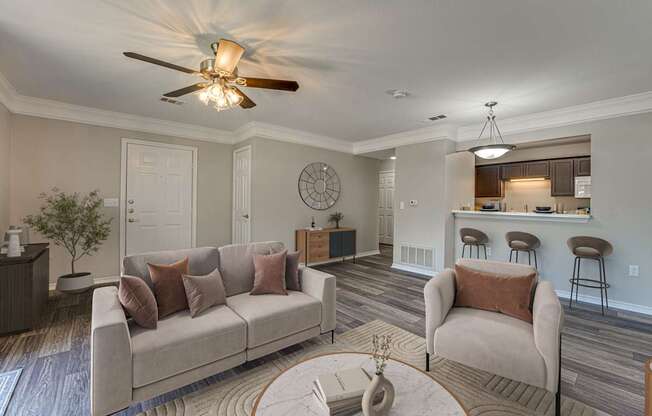 A living room with a couch, chairs, and a ceiling fan.