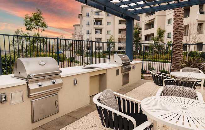 A patio with a grill and chairs under a pergola.