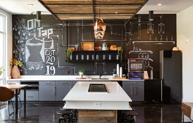 a kitchen with a large white island in front of a chalkboard wall at Abberly Noda Vista Apartment Homes, North Carolina, 28206