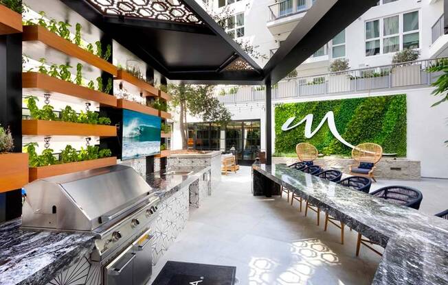 One of two lushly-landscaped courtyards with outdoor kitchen, bar seating, and TV