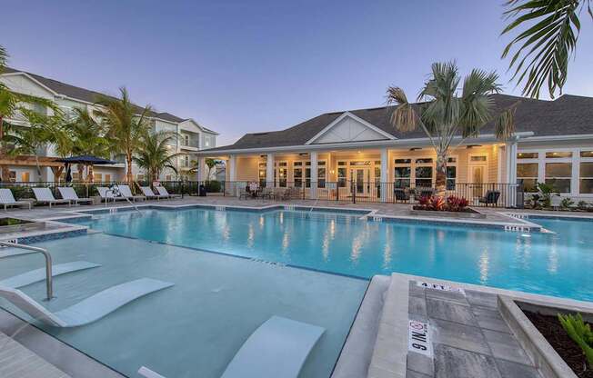 A large swimming pool in front of a building with palm trees.