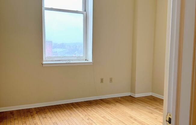 an empty room with a window and wooden floors