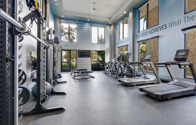 A gym with a variety of equipment including treadmills, weights, and exercise machines.