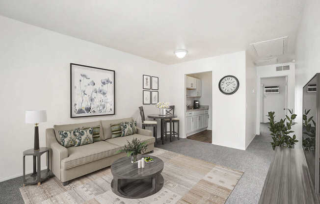 A living room with a couch, coffee table, and a painting on the wall at Newport Village Apartments, Portage, MI