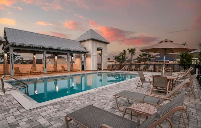 a resort style pool with lounge chairs and umbrellas