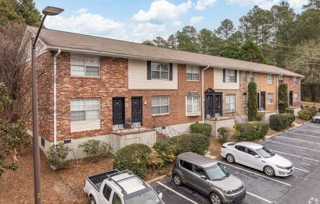 a brick apartment building with cars parked in a parking lot