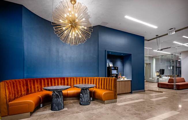 A modern office lobby with a blue wall and orange seating.