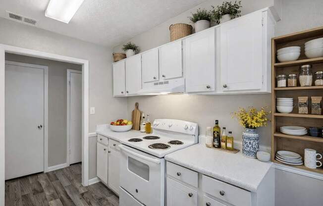 A kitchen with white cabinets and a white stove top oven.