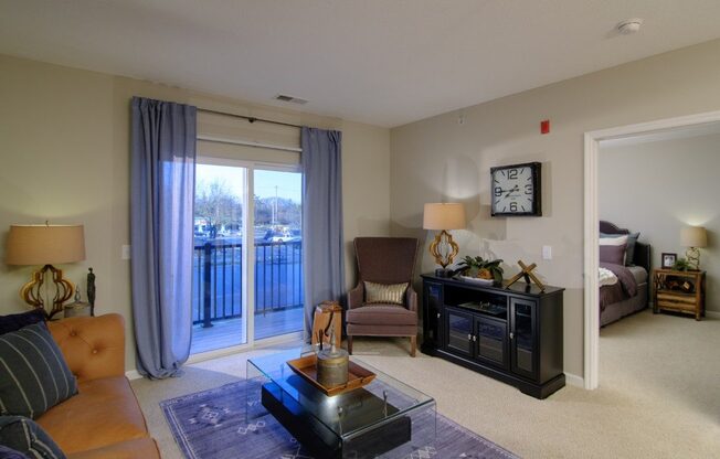 A living room with a brown couch, a coffee table, and a large window with curtains.