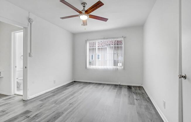 an empty living room with a window and a ceiling fan