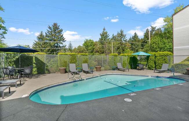 A small pool surrounded by a fence and trees.