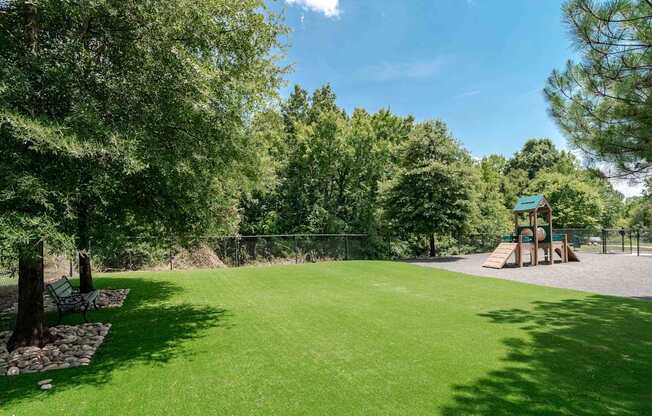 A playground with a green lawn and trees.