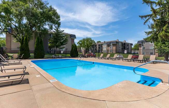 A swimming pool surrounded by lounge chairs and trees.