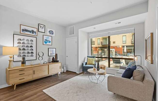 A living room with a couch, a table, a cabinet, and pictures on the wall.