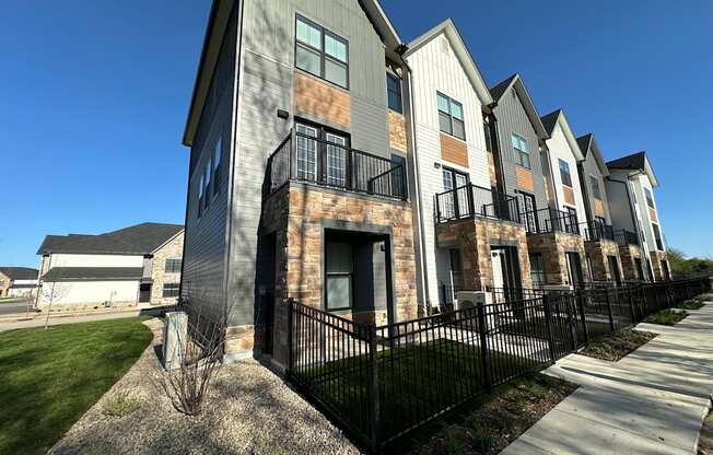 an exterior view of a row of apartments with a sidewalk and grass at The BLVD at Wilson Crossings, Wyoming, MI