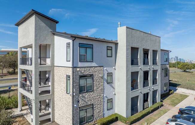 A modern apartment building with a parking lot in front.