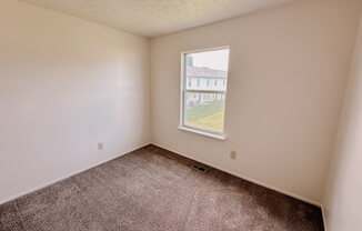 an empty room with a window and carpet