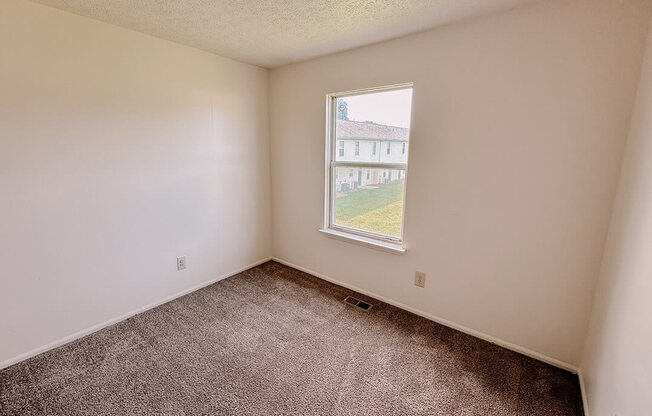 an empty room with a window and carpet