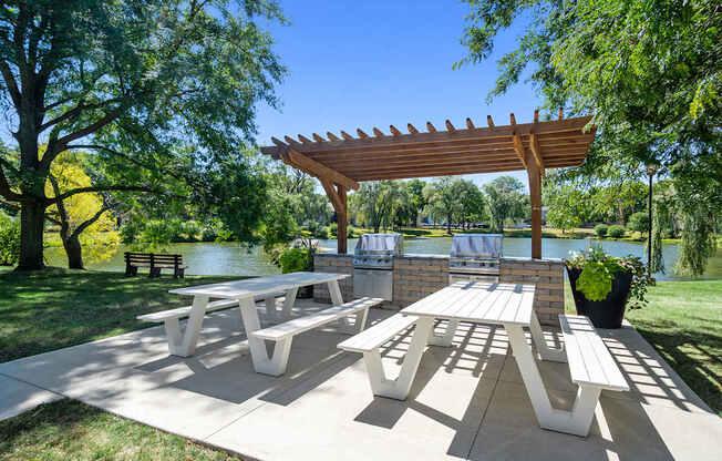 A wooden pergola shades a picnic table in a park.