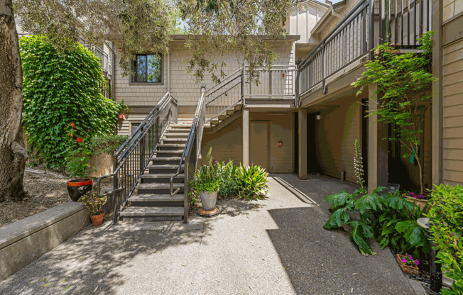 the entrance to a house with stairs and a yard with plants