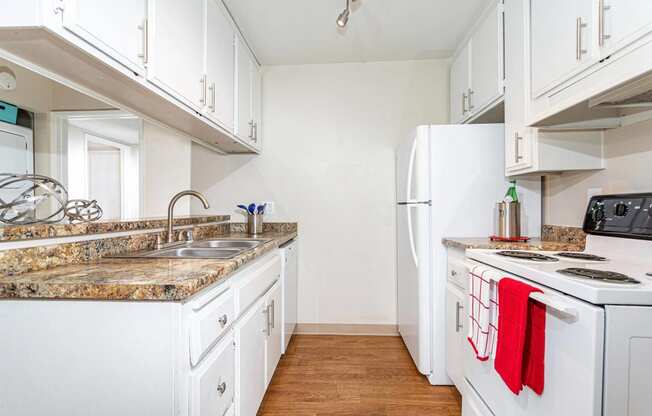 a kitchen with white appliances and granite counter tops and white cabinets