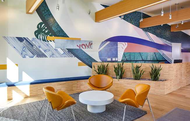 A room with a white table and orange chairs.