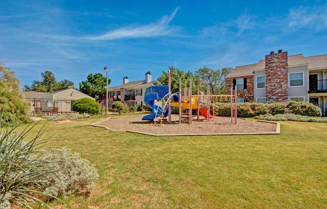 A spacious playground here at Cypress Pointe with colorful slides, climbing structures, and open play space set within a grassy lawn. Surrounding apartment homes and landscaped greenery create a safe, family-friendly outdoor environment for residents to enjoy.