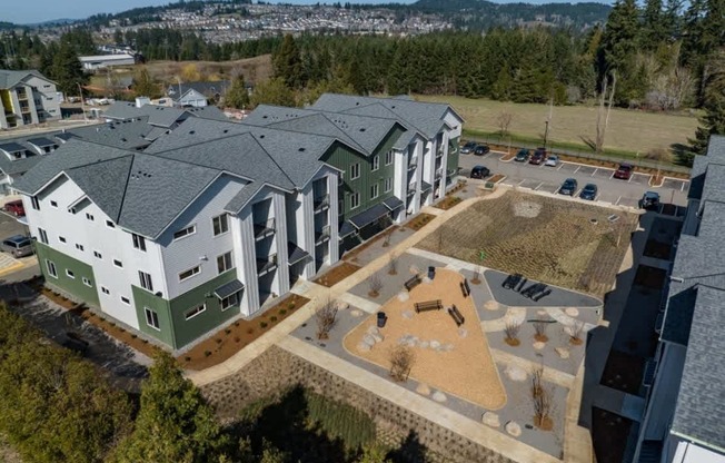 an aerial view of an apartment building with green and white buildings and a parking lot at Sonder Fields in Happy Valley, OR