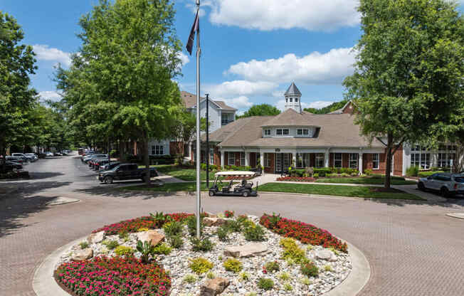 a flag pole in the middle of a flower garden in front of a house