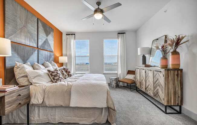 A bedroom with a large bed, a wooden dresser, and a ceiling fan.