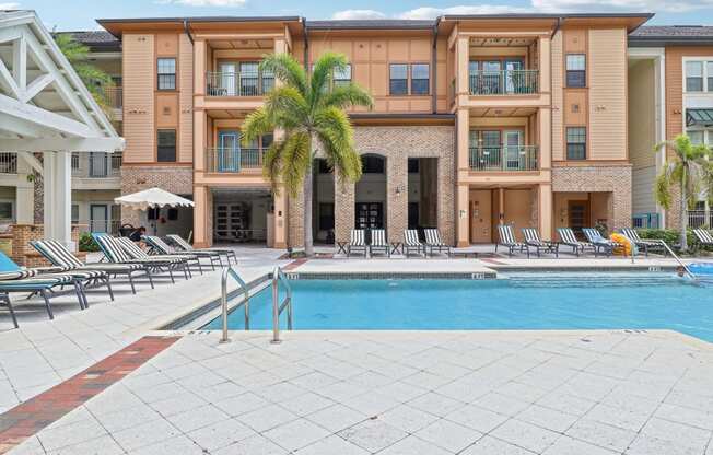 a swimming pool in front of a building with a resort style pool