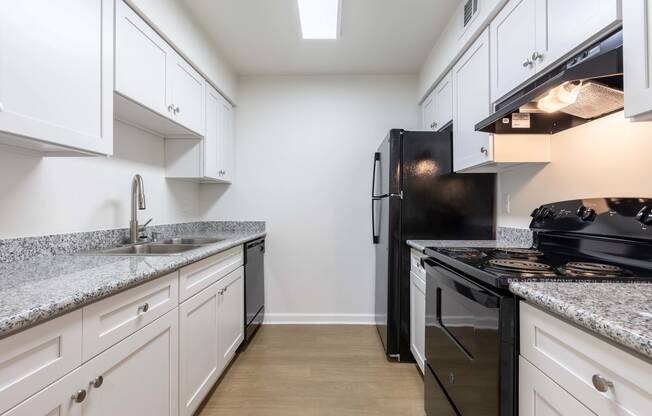 Whitney Manor Apartments in Gretna, LA photo of a kitchen with white cabinets and black appliances