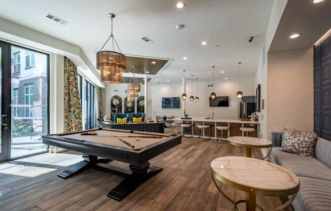 A billiard table is in the middle of a room with a couch and a table.