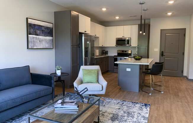 Furnished open concept living room looking into large kitchen in Bliss floor plan at Haven at Uptown in Lincoln.