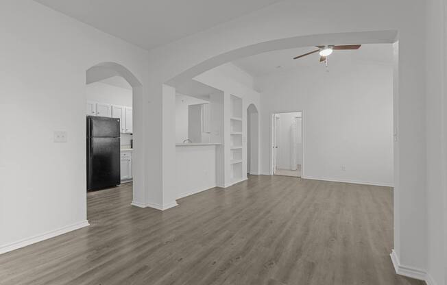 A spacious room with wooden flooring and white walls.