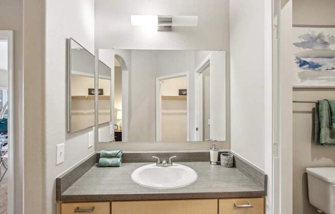 A bathroom with a sink, mirror, and towel rack.