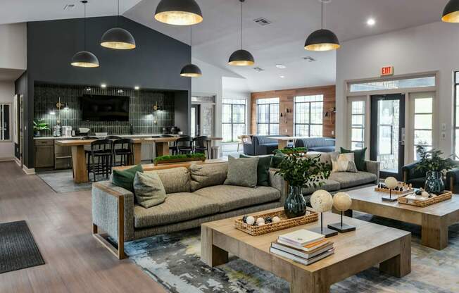 A modern living room with a grey couch, a wooden coffee table, and a bar area in the background.