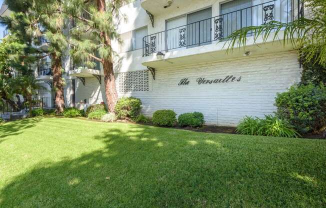 an image of the front of an apartment building with green grass and trees