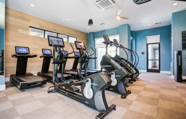 A gym with treadmills, elliptical machines, and other exercise equipment.