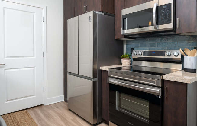 A modern kitchen with a stainless steel refrigerator, microwave, and oven.
