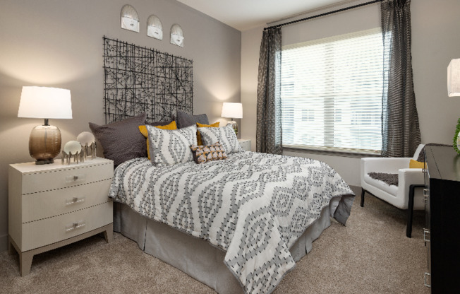 Model bedroom at our apartments for rent in Atlanta, featuring carpeted flooring and windows with blinds.