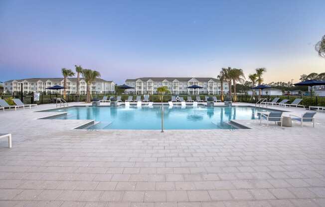 a large pool with chairs and chairs around it in front of a resort