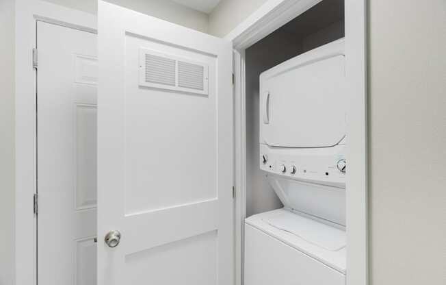 A white door is open to a white dryer.