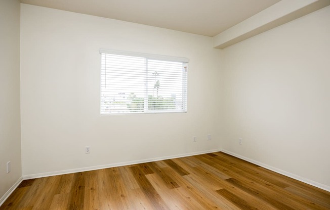 an empty room with wood floors and a window