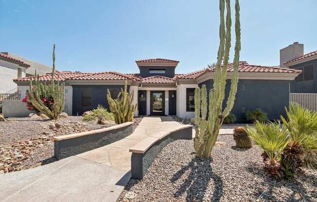 a house with a pathway and cactus in front of it