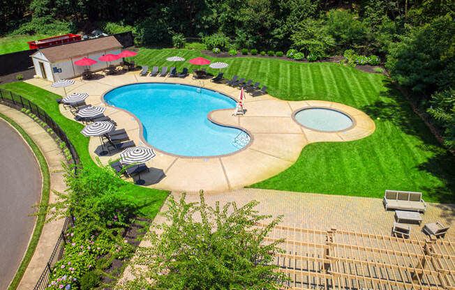 an aerial view of a pool and a backyard with chairs and umbrellas