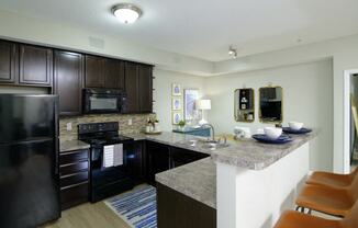 A kitchen with a black refrigerator and a black microwave.