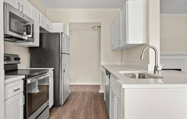 a renovated kitchen with white cabinets and stainless steel appliances at Villages of Cypress Creek, Texas, 77070