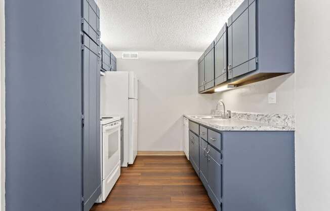 an empty kitchen with blue cabinets and a white refrigerator