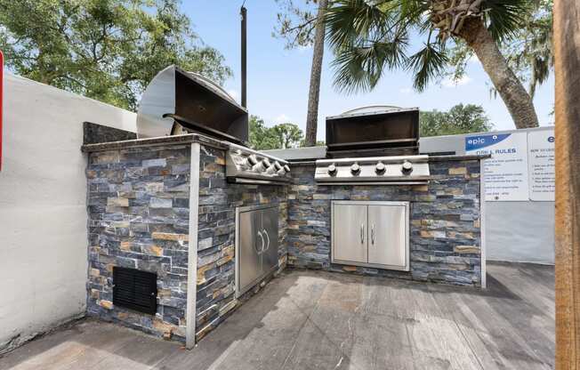 a barbecue grill with a stone wall and two stoves